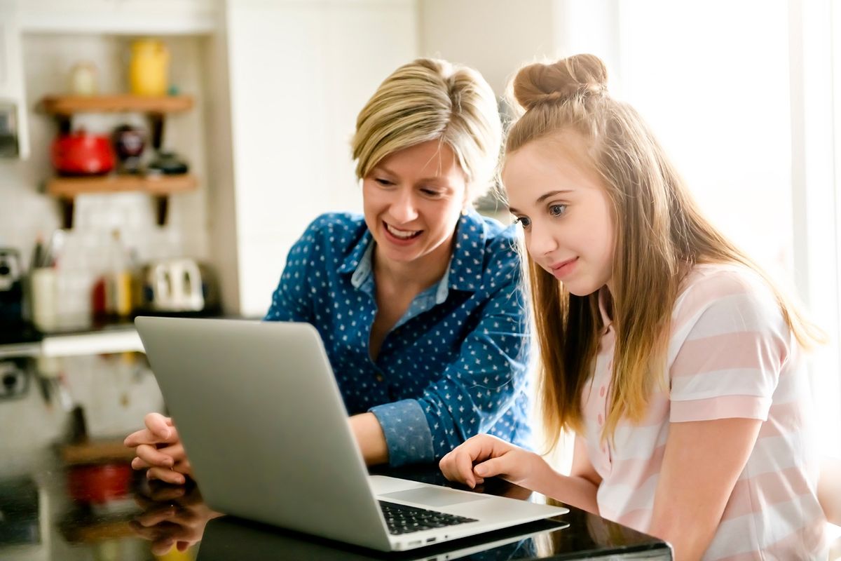 A,Mother,Using,A,Laptop,In,Kitchen,With,Teenager