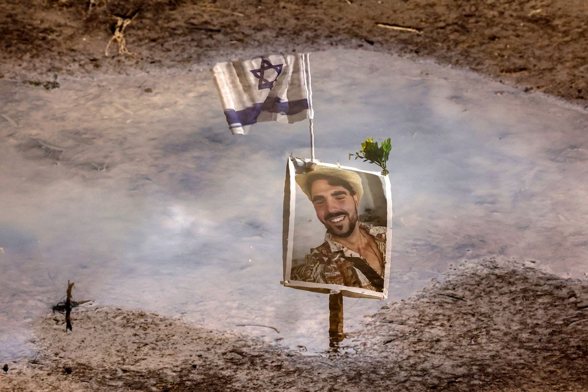 A portrait of a one of the people taken captive or killed by Hamas militants during the Supernova music festival attack on October 7, is reflected in the water during a visit at the site where the deadly incident took place near Kibbutz Reim in southern Israel, on January 11, 2024, amid continuing battles between Israel and Hamas in Gaza. (Photo by JACK GUEZ / AFP)