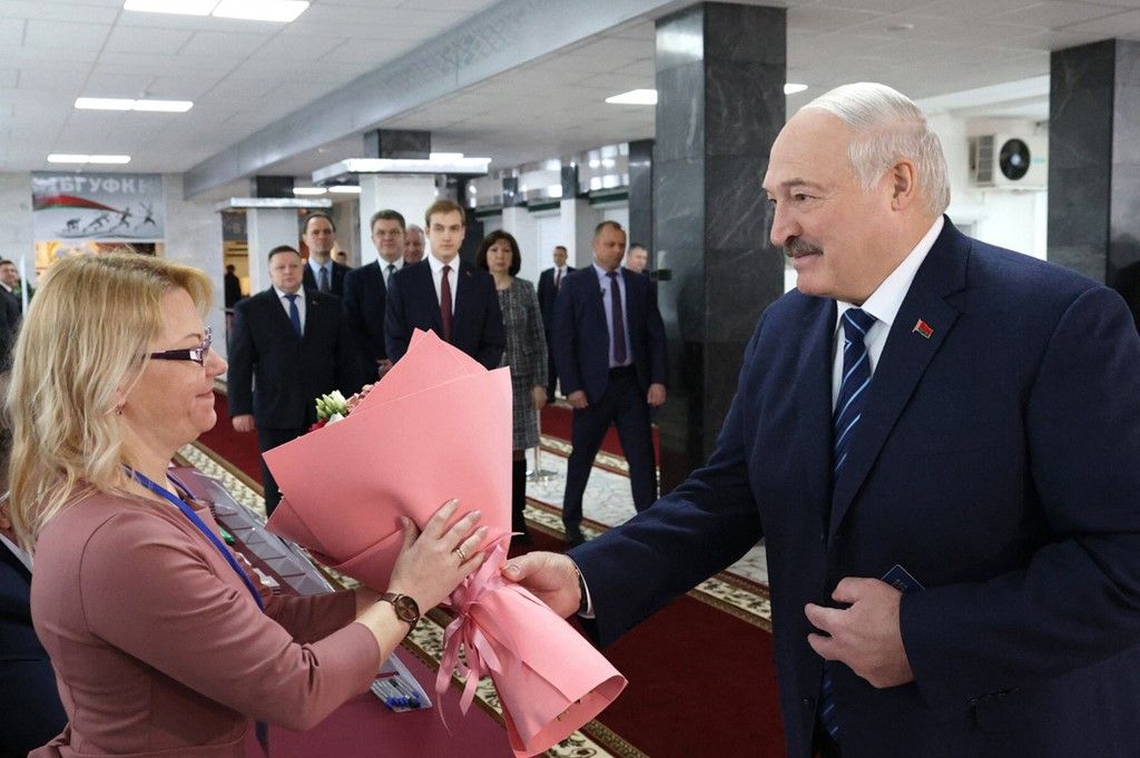 In this handout photograph taken and released by Belarusian presidential press service on February 25, 2024, Belarus' President Alexander Lukashenko (R) presents a bouquet of flowers to a member of an electoral commission as he arrives to vote during parliamentary elections at a polling station in Minsk. (Photo by Handout / Belarusian presidential press service / AFP) / RESTRICTED TO EDITORIAL USE - MANDATORY CREDIT "AFP PHOTO / Belarusian presidential press service" - NO MARKETING NO ADVERTISING CAMPAIGNS - DISTRIBUTED AS A SERVICE TO CLIENTS