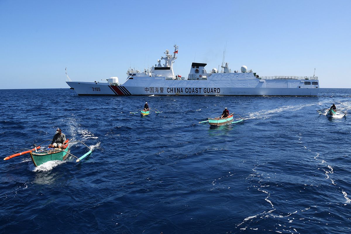 This photo taken on February 15, 2024 shows Filipino fishermen aboard their wooden boats sailing past a Chinese coast guard ship near the China-controlled Scarborough Shoal, in disputed waters of the South China Sea. The Philippines on February 17 accused Chinese coast guard vessels of "dangerous" manoeuvres for attempting to block a Filipino vessel dropping supplies to fishermen at a reef off the Southeast Asian nation's coast. (Photo by Ted ALJIBE / AFP)