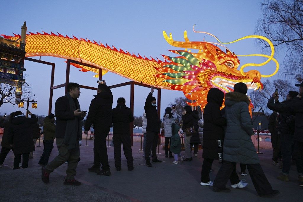 People gather to look at a giant dragon figure at a park in Beijing on February 9, 2024, which marks the eve of the Lunar New Year of the Dragon. (Photo by GREG BAKER / AFP)