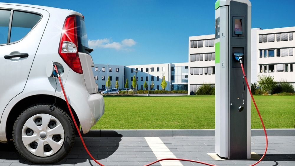 Electric,Car,On,Charging,Spot,In,Front,Of,Architecture,Office