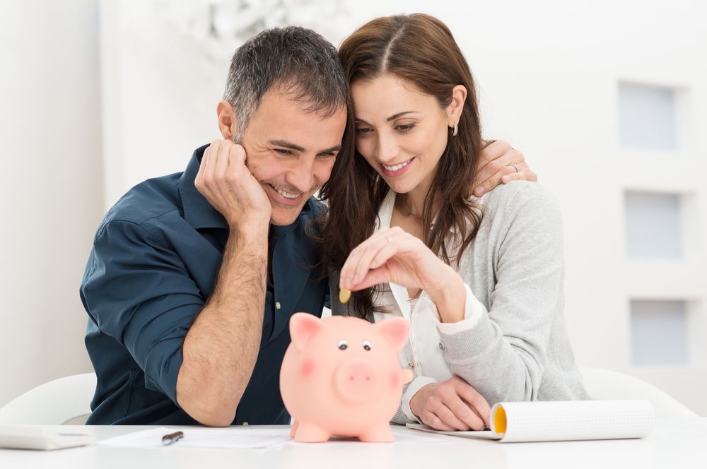 Portrait,Of,Happy,Couple,Inserting,Coin,In,Piggybank