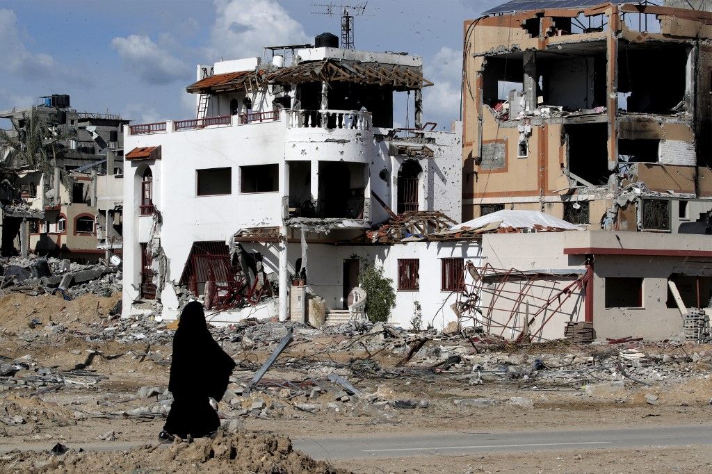 A woman walks past a destroyed building in the Maghazi camp for Palestinian refugees, which was severely damaged by Israeli bombardment amid the ongoing conflict in the Gaza Strip between Israel and the Palestinian militant group Hamas, in the central Gaza Strip on February 1, 2024. (Photo by ANAS BABA / AFP)