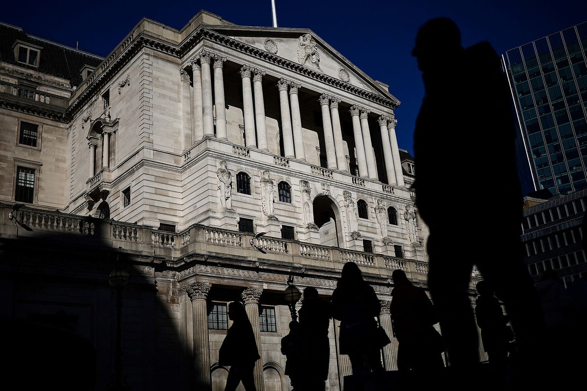 Pedestrians cross the streets in front of The Bank of England illuminated by a ray of sunlight, in central London, on February 12, 2024. (Photo by HENRY NICHOLLS / AFP)