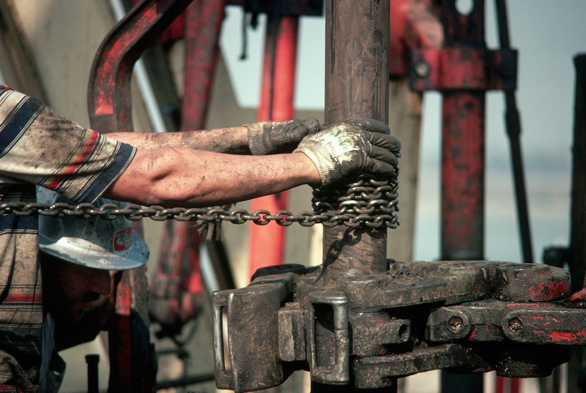 An oil worker's arms reach toward a well drill, at an oil field in Southern California.
