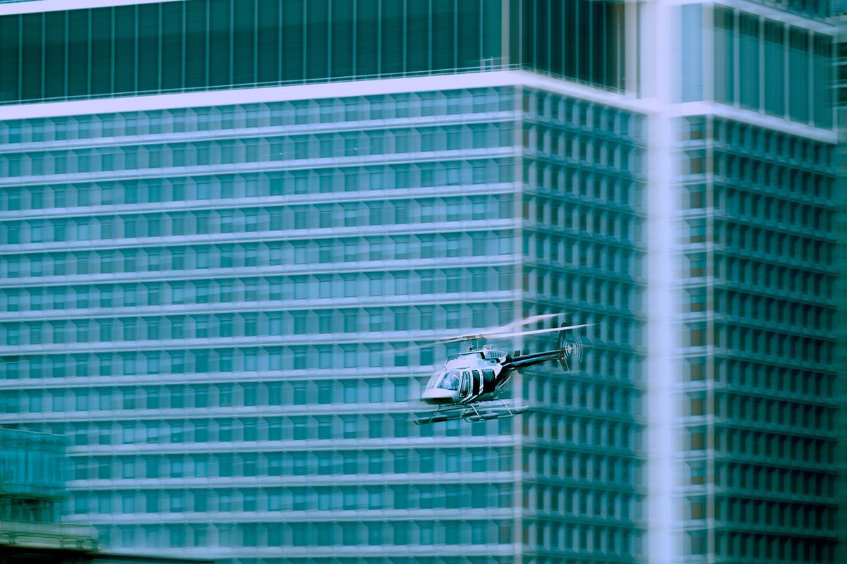 private helicopter flying around buildings, privát helikopter