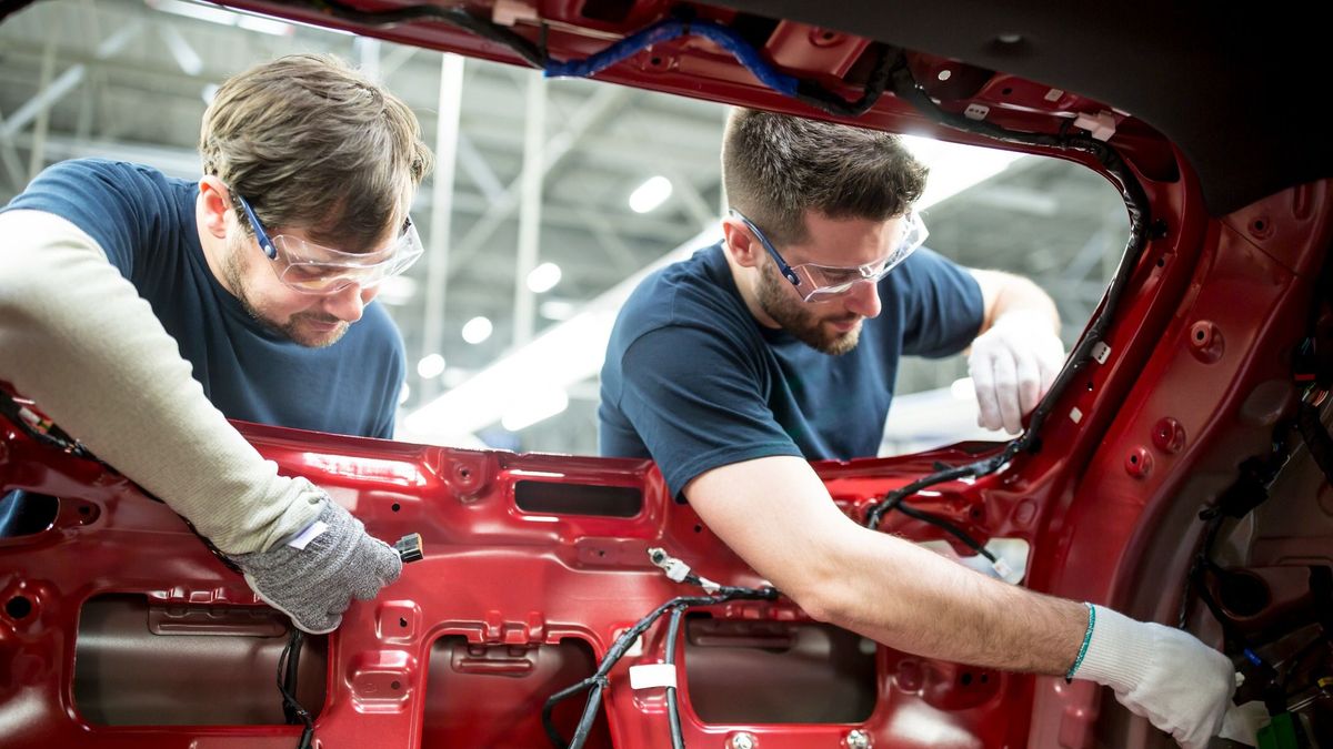 Two colleagues working at bodywork in modern car factory német