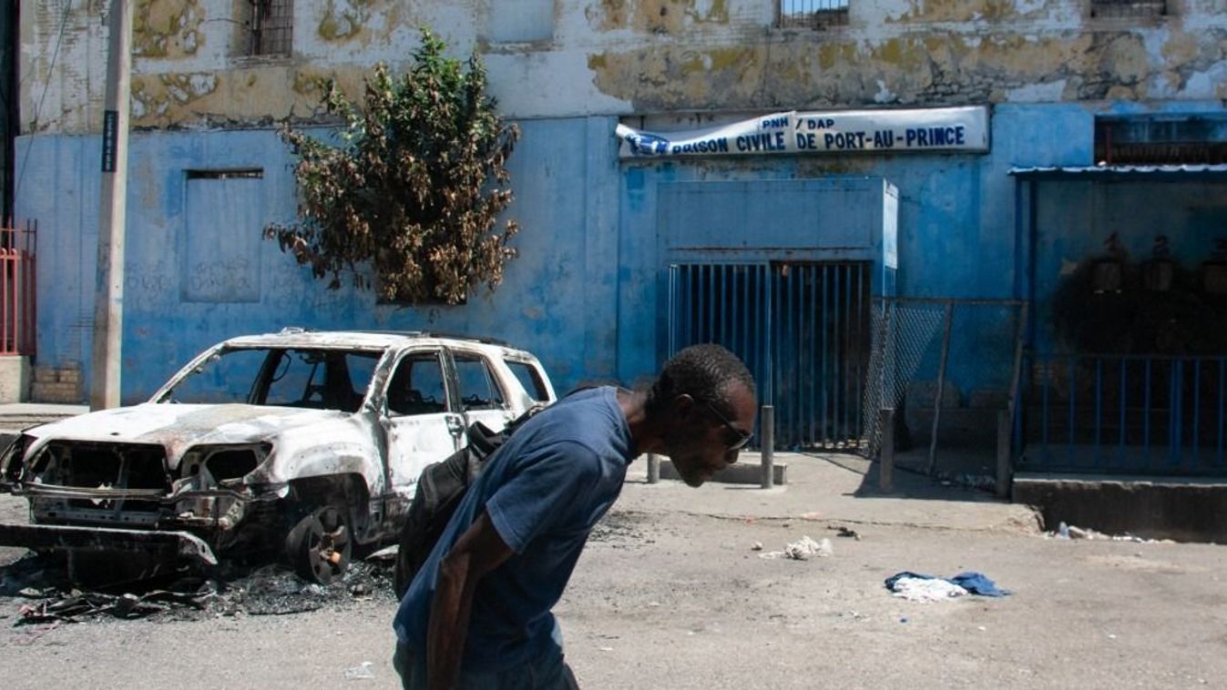 Haiti schools and banks shut as state of emergency tightensA man leaves the prison area and lowers his head because of the nearby gunfire, in Port-au-Prince, Haiti, March 4, 2024. At least a dozen people died as gang members attacked the main prison in Haiti's capital, triggering a breakout by several thousand inmates, an AFP reporter and an NGO said on March 3. "We counted many prisoners' bodies," said Pierre Esperance of the National Network for Defense of Human Rights, adding that only around 100 of the National Penitentiary's estimated 3,800 inmates were still inside the facility after the gang assault overnight on March 2. (Photo by Clarens SIFFROY / AFP)