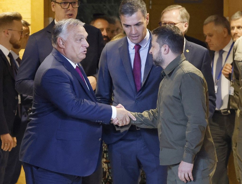 Ukraine's President Volodymyr Zelensky (R) shakes hands with Hungary's Prime Minister Viktor Orban (L) next to Spain's acting Prime Minister Pedro Sanchez (back, R) before the start of a plenary session of the European Political Community summit at the Palacio de Congreso in Granada, southern Spain on October 5, 2023. Europe's quest to build a common geopolitical purpose brought four dozen of its leaders to Granada, but its credibility suffered a blow when the Azerbaijani president stayed away. (Photo by Ludovic MARIN / AFP)