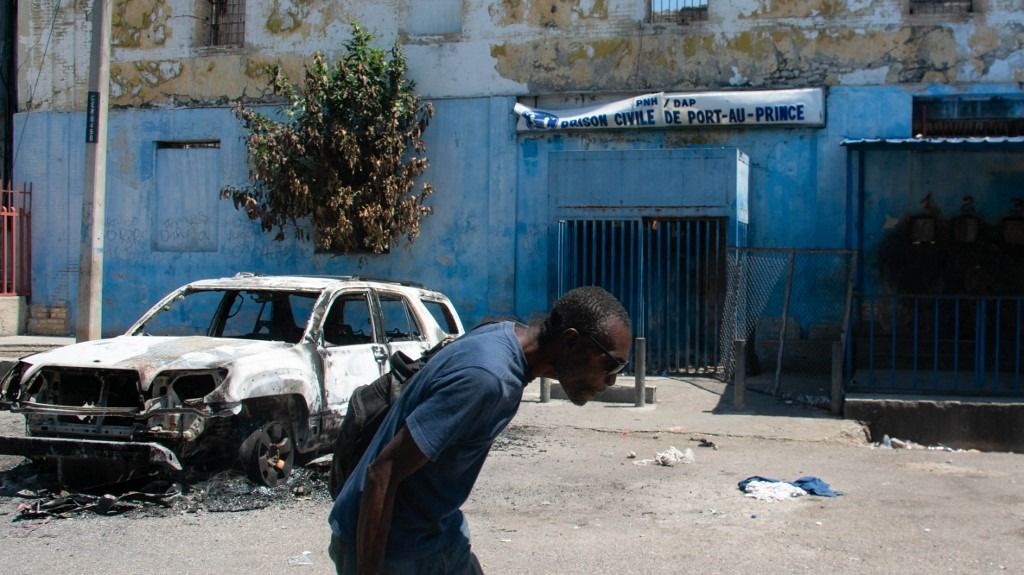 Haiti schools and banks shut as state of emergency tightensA man leaves the prison area and lowers his head because of the nearby gunfire, in Port-au-Prince, Haiti, March 4, 2024. At least a dozen people died as gang members attacked the main prison in Haiti's capital, triggering a breakout by several thousand inmates, an AFP reporter and an NGO said on March 3. "We counted many prisoners' bodies," said Pierre Esperance of the National Network for Defense of Human Rights, adding that only around 100 of the National Penitentiary's estimated 3,800 inmates were still inside the facility after the gang assault overnight on March 2. (Photo by Clarens SIFFROY / AFP)