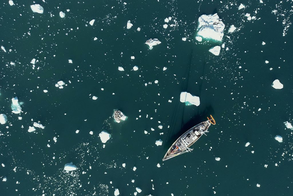 Egy tudományos expedíciós vitorlás, a Kamak olvadó jéghegyek töredékei között navigál a grönlandi Scoresby-fjordban 2023. augusztus 16-án.  The French National Centre for Scientific Research (CNRS) is undertaking an expedition to explore Greenland's isolated fjords, the planet's largest fjord system, which remains vastly understudied. The expedition, arranged by the volunteer-run French initiative Greenlandia, is dedicated to understanding the climate change's effects on Scoresby Fjord and its inhabitants. (Photo by Olivier MORIN / AFP)