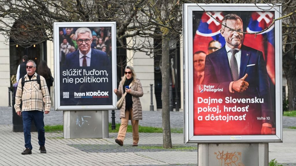 A couple walk by election posters of two presidential