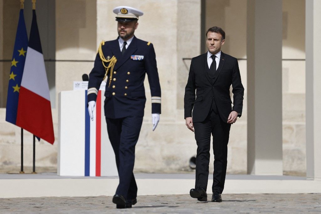 France's President Emmanuel Macron (R) walks during a "national tribute" ceremony to late French politician and admiral, Philippe de Gaulle, the son of Charles de Gaulle, with his portrait displayed on a facade, at the Hotel des Invalides in Paris on March 20, 2024. Admiral Philippe de Gaulle, son of General de Gaulle, died in Paris at the age of 102, his family said on March 13, 2024. (Photo by Ludovic MARIN / POOL / AFP)