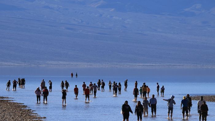 A turisták élvezik a ritka lehetőséget, hogy térdig sétáljanak sós vízben, miközben 2024. február 18-án ellátogatnak Badwater-medencébe, az Egyesült Államok általában legszárazabb helyére a Death Valley Nemzeti Parkban, Inyo megyében, Kaliforniában.  It is the lowest point in North America, at 282 feet (86 meters) below sea level. (Photo by David SWANSON / AFP)