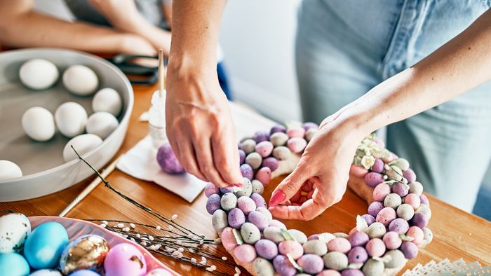 Close-up of women's hands making a wreath of eggs for Easter.