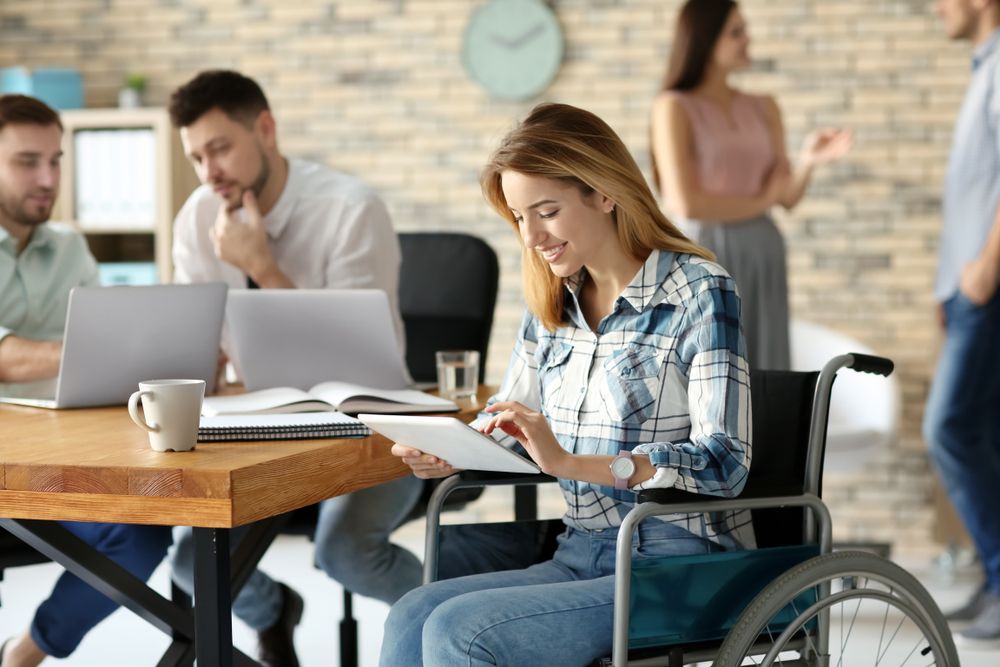 Young,Woman,In,Wheelchair,And,Colleagues,At,Workplace