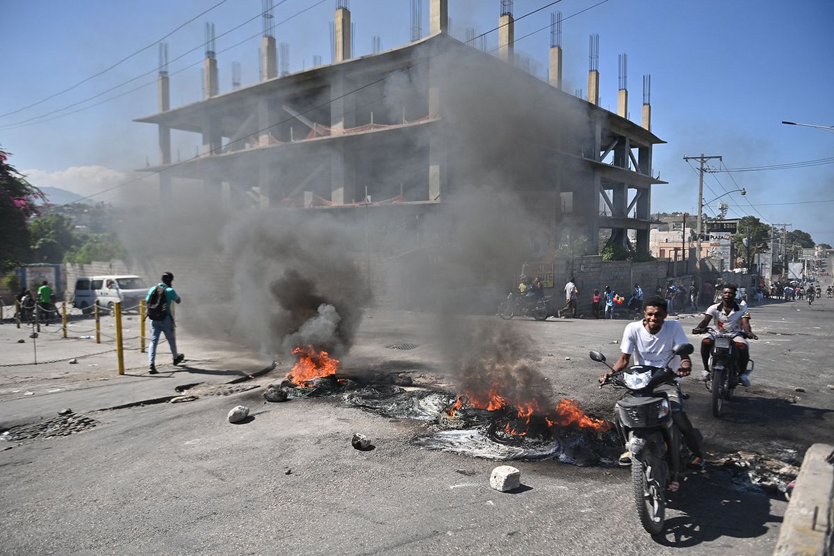 A motorcyclist passes by burning tires in Delmas 30, Port-au-Prince, Haiti during a day of uprising against the Haitian prime minister, January 18, 2024. (Photo by Richard PIERRIN / AFP)