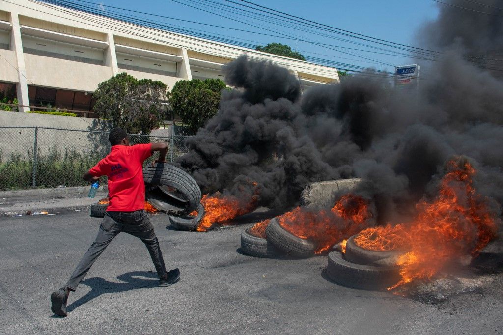 A protester burns tires during a demonstration following the resignation of its Prime Minister Ariel Henry, in Port-au-Prince, Haiti, on March 12, 2024. A political transition deal in Haiti marks a key step forward for the violence-ravaged country but far more needs to be done, with some experts warning the situation could deteriorate further. (Photo by Clarens SIFFROY / AFP)