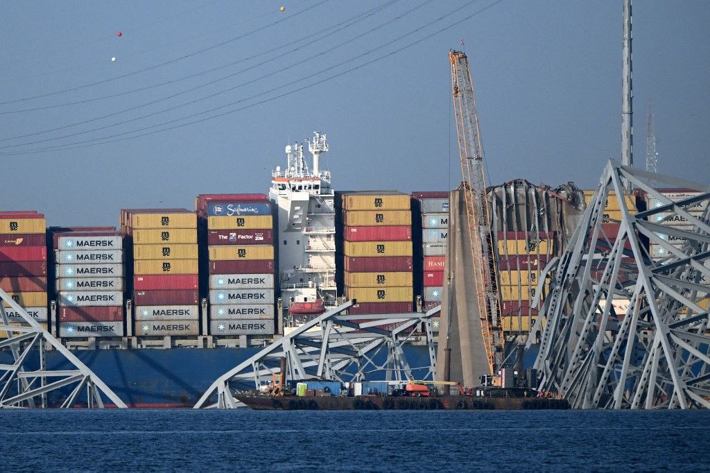 A crane begins clean-up at the collapsed Francis Scott Key Bridge after it was struck by the container ship Dali, in Baltimore, Maryland, on March 29, 2024. Cranes began arriving March 28 at the scene of the catastrophic bridge collapse over Baltimore harbor, as authorities shifted to a clean-up phase of the recovery and warned of extensive work before the major US port can reopen. Four men, all Latin American immigrants, are believed to have been killed when the Singapore-flagged container ship lost power and careened into a bridge support column. (Photo by Mandel NGAN / AFP)