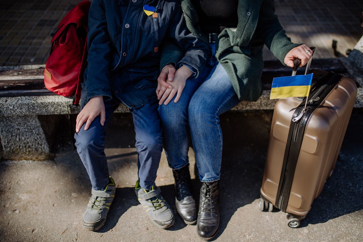 Low section of Ukrainian refugee family sitting in station when waiting to leave Ukraine due to the Russian invasion of Ukraine.Ukrainian refugee family waiting for train in station, Ukrainian war concept.