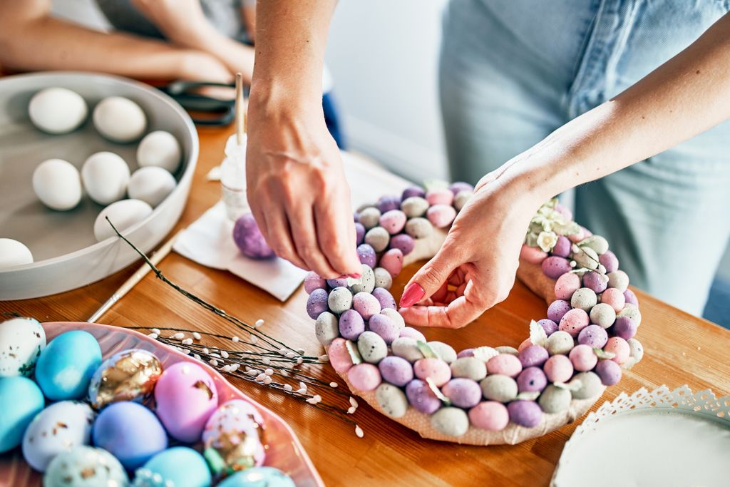 Close-up of women's hands making a wreath of eggs for Easter.