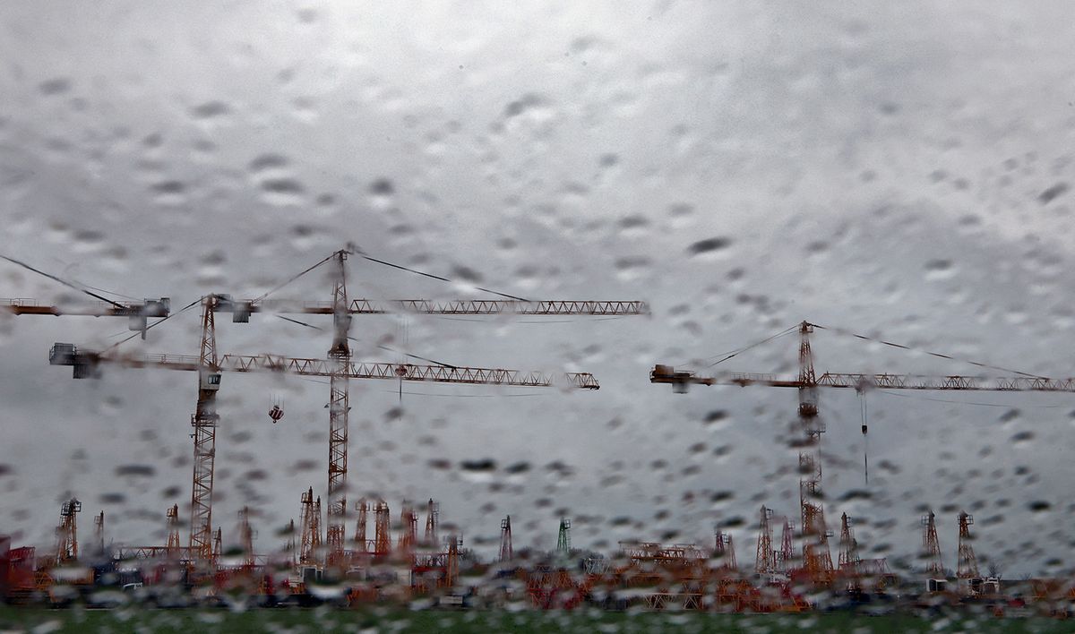 18 March 2024, Bavaria, Mindelheim: Behind a rain-soaked window, construction cranes can be seen on the site of a crane service under thick clouds. Photo: Karl-Josef Hildenbrand/dpa (Photo by KARL-JOSEF HILDENBRAND / DPA / dpa Picture-Alliance via AFP)