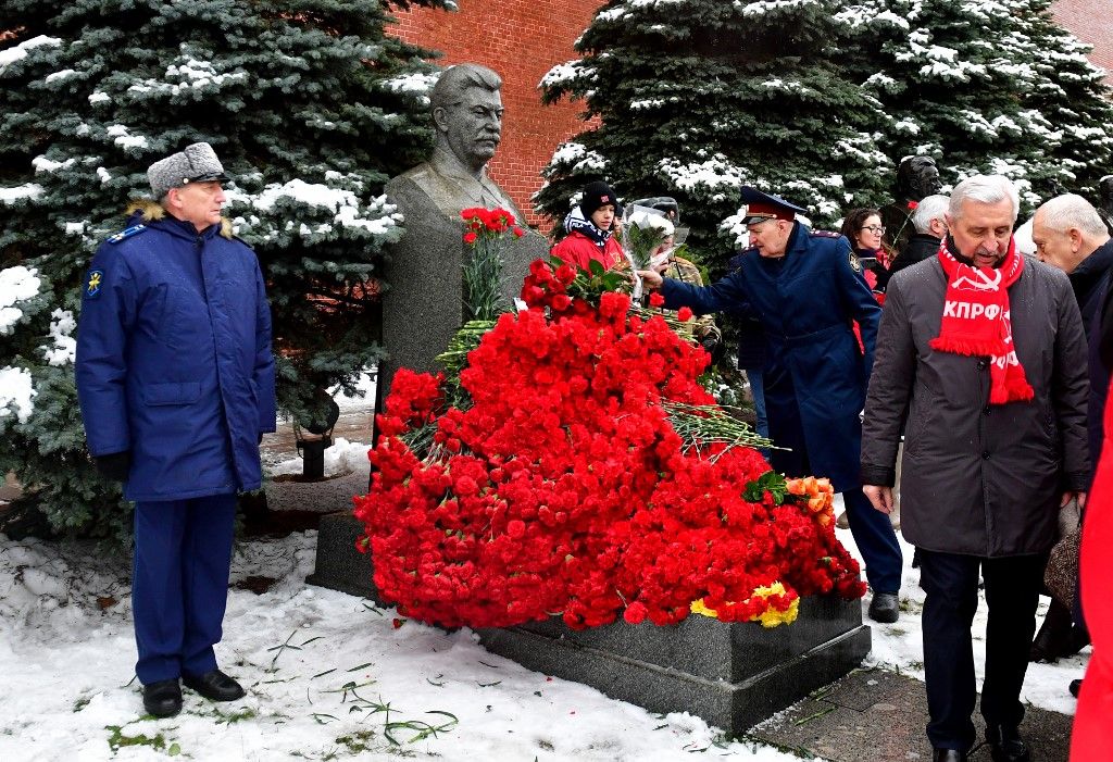 Russian Communist party supporters lay flowers to the tomb of late Soviet leader Joseph Stalin during a memorial ceremony to mark the 144th anniversary of his birth at Red Square in Moscow on December 21, 2023. While historians blame Stalin for the deaths of millions in purges, prison camps and forced collectivisation, many in Russia still praise him for leading the Soviet Union to victory over Nazi Germany in World War II. (Photo by Olga MALTSEVA / AFP)