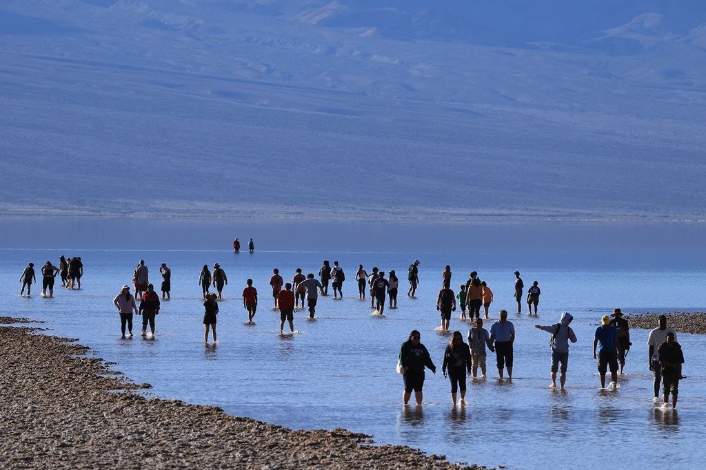 A turisták élvezik a ritka lehetőséget, hogy térdig sétáljanak sós vízben, miközben 2024. február 18-án ellátogatnak Badwater-medencébe, az Egyesült Államok általában legszárazabb helyére a Death Valley Nemzeti Parkban, Inyo megyében, Kaliforniában.  It is the lowest point in North America, at 282 feet (86 meters) below sea level. (Photo by David SWANSON / AFP)