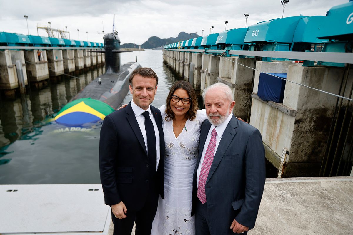 French President Emmanuel Macron (L), his Brazilian counterpart, Luiz Inacio Lula da Silva (R), and Brazilian First Lady Rosangela Janja Da Silva pose next to the Tonelero submarine during its launch at the Itaguai naval base in Itaguai, Rio de Janeiro State, Brazil, on March 27, 2024. President Emmanuel Macron told Brazil Wednesday France was "at your side" as the country seeks to develop nuclear-powered submarines, but without announcing specific collaboration on nuclear propulsion technology that Brasilia has pushed for. Macron was speaking during a ceremony to launch Brazil's third French-designed submarine, which will help secure the country's long coastline, dubbed the "Blue Amazon." (Photo by Ludovic MARIN / POOL / AFP)