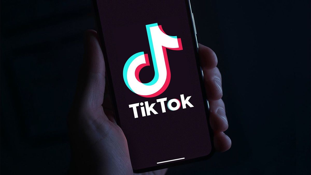 Hand,Holding,Phone,With,The,Tiktok,Logo,In,Front,Of influenszer