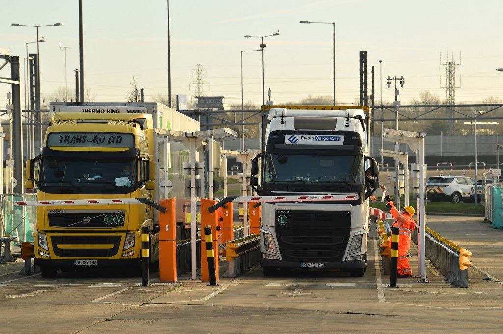 A driver hands out documents for checking at the 'pit stop' for documentation checks before heading to passport control at the Eurotunnel terminal at Folkestone, Southeast England, on December 31, 2020 the day that Britain leaves the EU single market and customs union. The White Cliffs of Dover, which on a clear day are visible from France less than 30 miles (nearly 50 kilometres) across the Channel, have long been a symbol of Britain. Now, the nearby town, which can trace its history back to Roman times, and its busy port are on the frontline as Britain embarks on a new future outside the European Union. (Photo by Glyn KIRK / AFP)