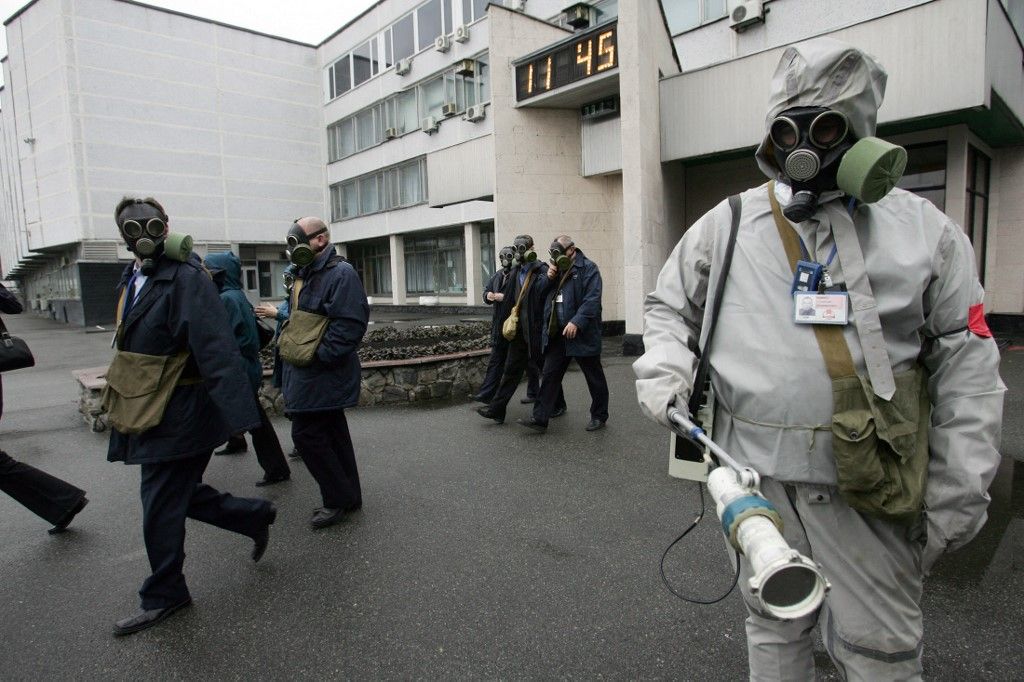 Chernobyl nuclear power plant employees wear gas masks as they leave their work areas during a drill organized by Ukraine's Emergency Ministry 08 November 2006. Emloyees and rescue workers improved their reactivity in case of collapse of the sarcophagus covering the destroyed 4th power block. AFP PHOTO/ SERGEI SUPINSKY (Photo by SERGEI SUPINSKY / AFP)