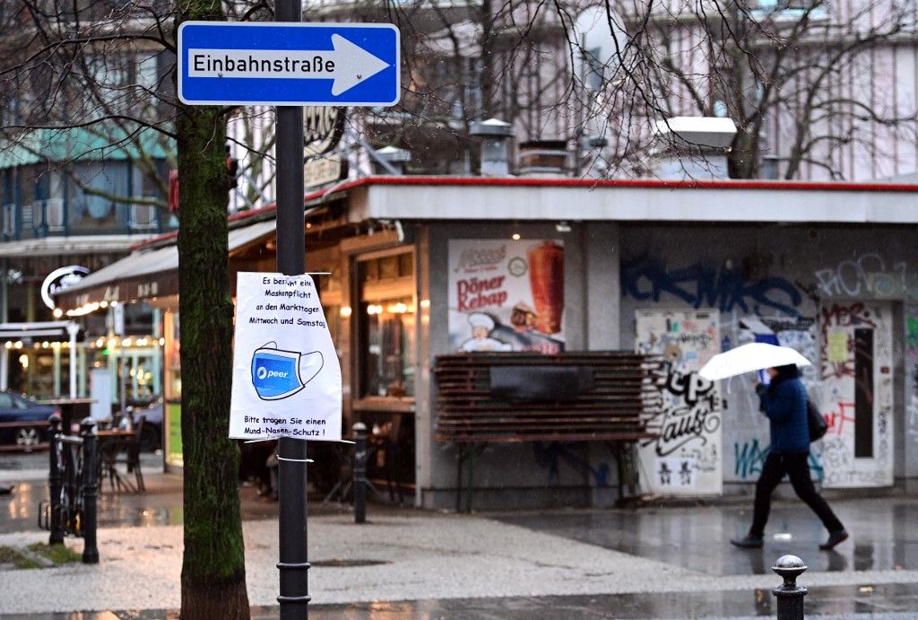 Coronavirus - BerlinPRODUCTION - 01 February 2022, Berlin: A passerby walks past a kebab snack bar in the rain on Winterfeldtplatz in the Schöneberg district of Tempelhof-Schöneberg, Berlin. In the foreground hangs a sign urging people to wear a mask during the market. The total number of detected Corona infections in Germany has exceeded the ten million mark. Photo: Soeren Stache/dpa-Zentralbild/dpa (Photo by SOEREN STACHE / dpa-Zentralbild / dpa Picture-Alliance via AFP) migráns, vendégmunkás