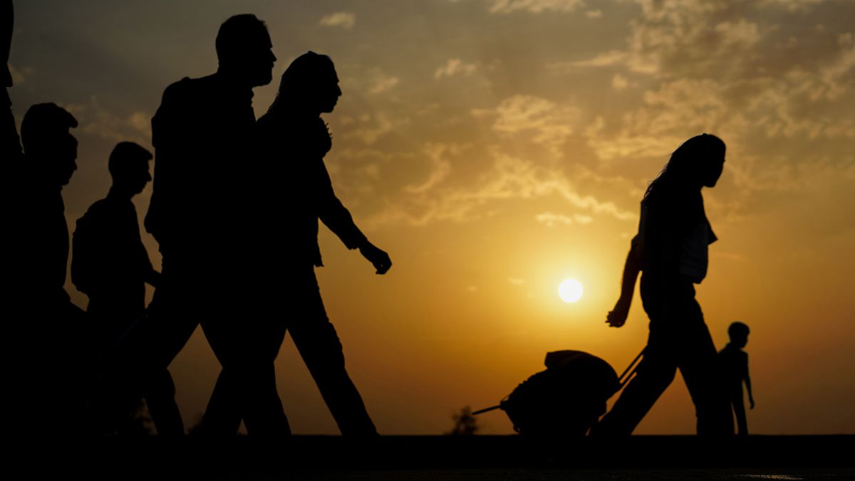 Silhouette of people crossing land on sunset, refugees