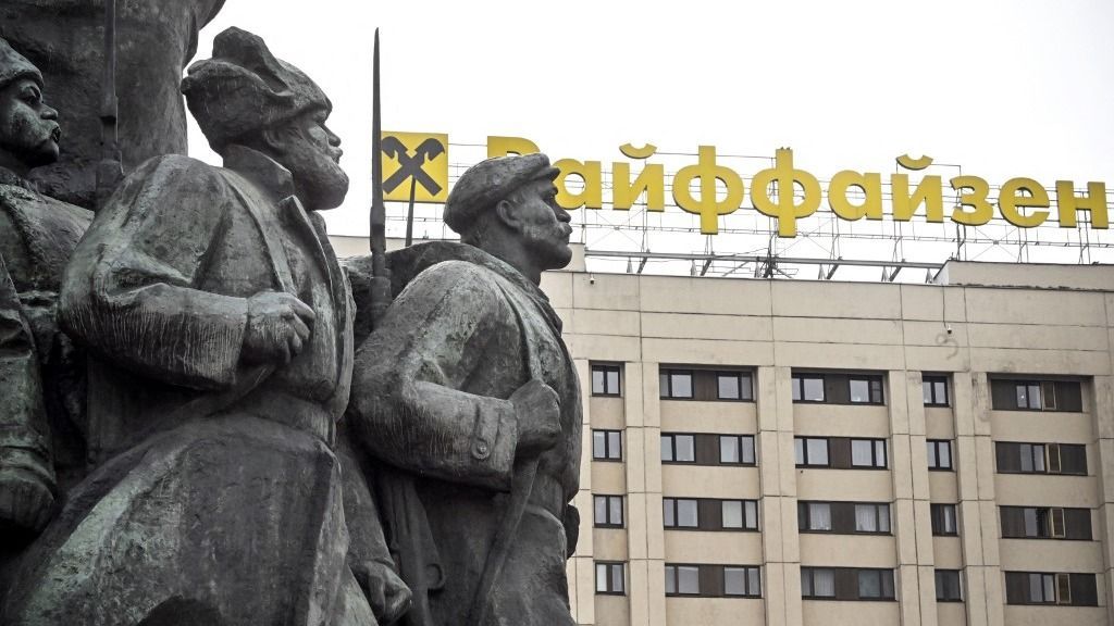 The logo of Raiffeisen bank is seen atop a building behind revolutionary militiamen - a fragment of a huge monument to Vladimir Lenin, the founder of the USSR, in Moscow on April 3, 2023. Austrian banking group Raiffeisen, one of the last major Western banks in Russia, said on March 30, 2023 it was considering a "sale or spin-off" of its subsidiary. "The RBI Group will continue to progress potential transactions which would result in the sale or spin-off of Raiffeisenbank Russia and deconsolidation of Raiffeisenbank Russia from the RBI Group," the company said, while "committing to further reducing business activity in Russia." (Photo by Alexander NEMENOV / AFP)