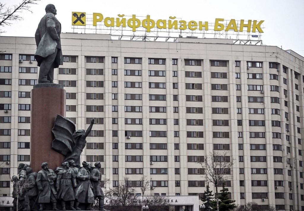 The logo of Raiffeisen bank is seen atop a building behind a huge monument to Vladimir Lenin, the founder of the USSR, in Moscow on April 3, 2023. Austrian banking group Raiffeisen, one of the last major Western banks in Russia, said on March 30, 2023 it was considering a "sale or spin-off" of its subsidiary. "The RBI Group will continue to progress potential transactions which would result in the sale or spin-off of Raiffeisenbank Russia and deconsolidation of Raiffeisenbank Russia from the RBI Group," the company said, while "committing to further reducing business activity in Russia." (Photo by Alexander NEMENOV / AFP)