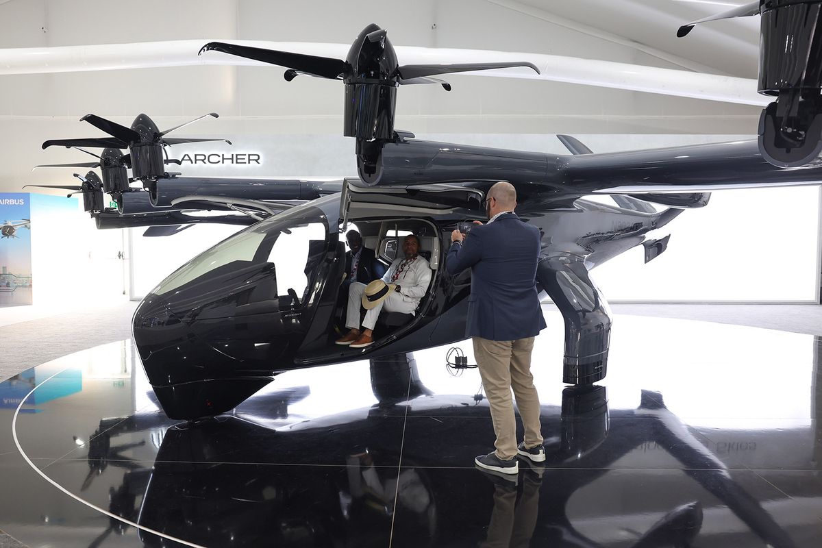 Attendees sit inside an Archer Aviation Inc. Midnight electric vertical take-off and landing (eVTOL) aircraft at the Dubai Air Show in Dubai, United Arab Emirates, on Monday, Nov. 13, 2023. The 2023 Dubai Air Show kicked off on Monday with high expectations of large deals, continuing the prevailing theme of this year that's seen airlines commit to huge orders. Photographer: Christopher Pike/Bloomberg via Getty Images
