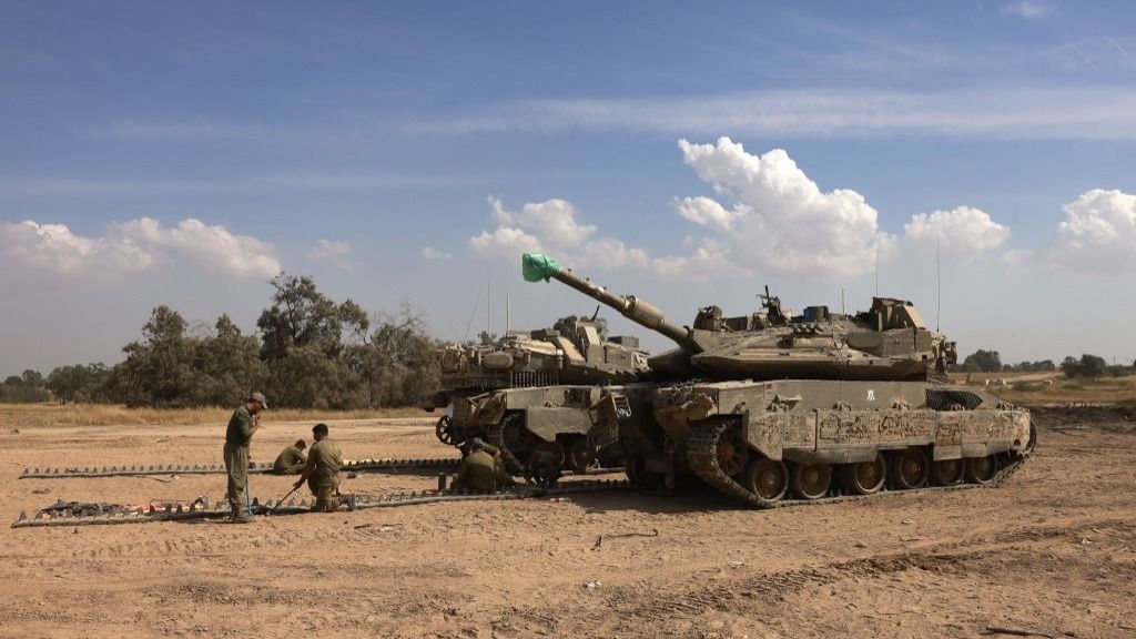 Israeli soldiers work on their tanks in a army camp near Israel's border with the Gaza Strip on April 8, 2024, amid the ongoing conflict between Israel and the militant group Hamas. (Photo by Menahem Kahana / AFP)