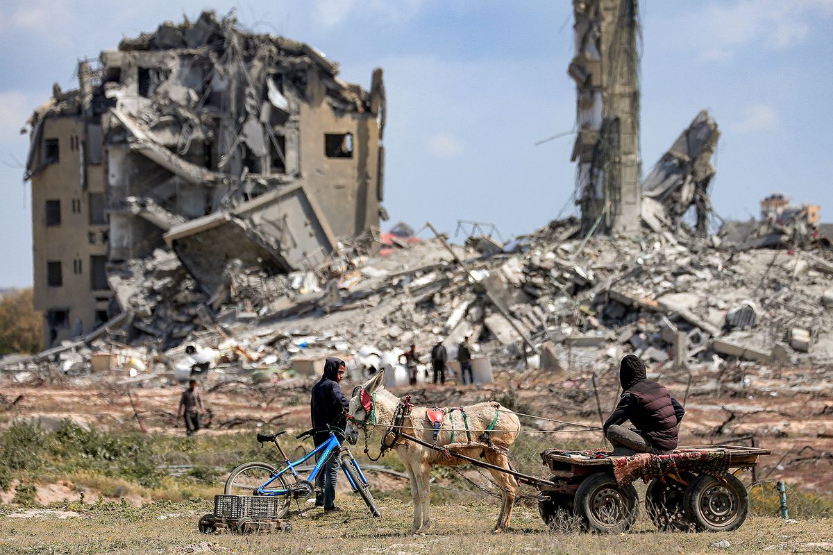 A person sits on a donkey-drawn cart while watching from a far as people search the rubble of destroyed buildings in the Asra residential compound, northwest of Nuseirat in the Gaza Strip, on March 25, 2024 amid the ongoing conflict in the Palestinian territory between Israel and the militant group Hamas. (Photo by AFP)