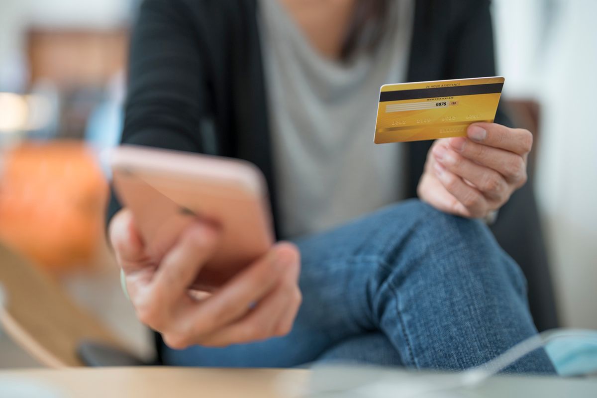 Close up of young woman sitting in a cafe and holding credit card and smart phone.
átutalás