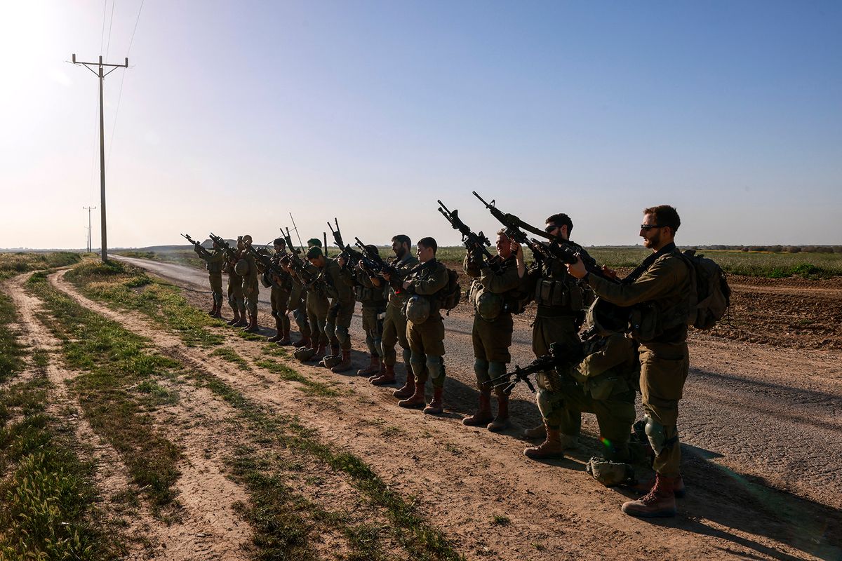 Israeli soldiers unload their guns after coming out from the Gaza Strip, near the border in southern Israel on March 12, 2024, amid the ongoing battles between Israel and the Palestinian militant group Hamas. (Photo by Menahem Kahana / AFP)