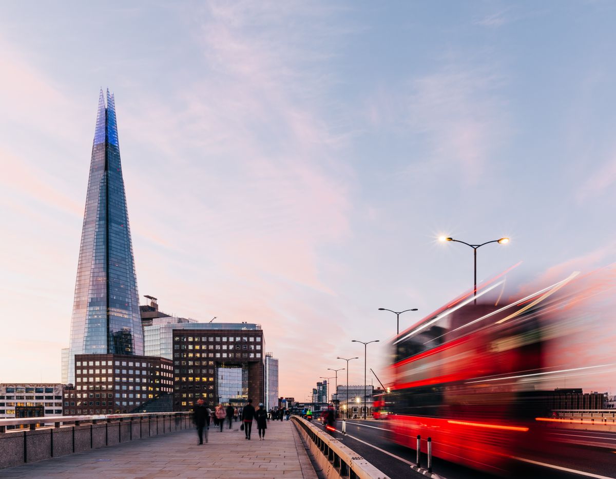 A sunrise view of London Bridge with blurred traffic and passer's by