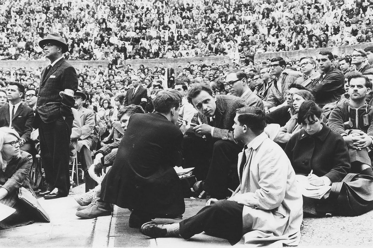 Free Speech Movement Photographs Collection, 1964-1984, bulk 1964 Group 2 Mario Savio in the Hearst Greek Theater. Mario Savio in the Hearst Greek Theater. Dec. 7, 1964 Unit ID: UARC PIC 24B:1:25 Description Bettina Aptheker is sitting behind Savio. Sidne