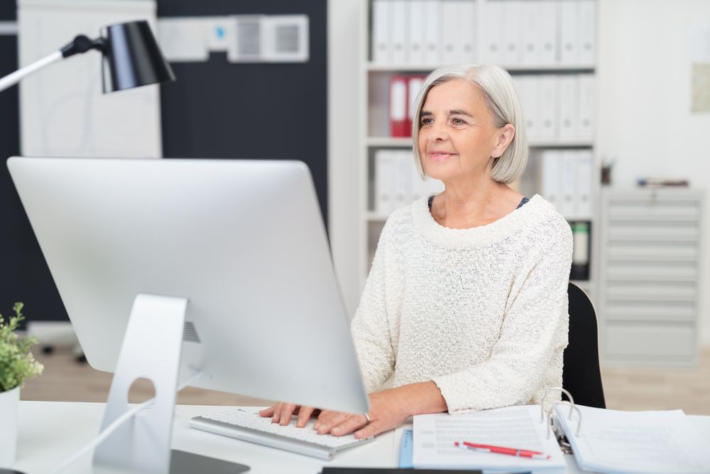 Senior,Businesswoman,At,Work,In,The,Office,Seated,At,Her
