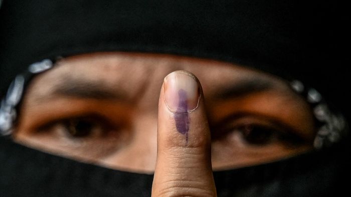 Egy nő tintával festett ujját mutatja, miután leadta a voksát egy szavazóhelyiségben az indiai általános választás második szakaszában, Bengaluruban