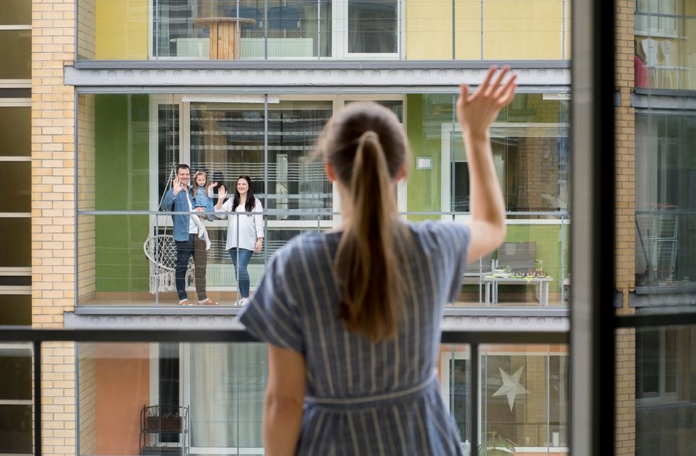 Back,View,Of,Woman,Standing,On,Balcony,Waving,To,Her