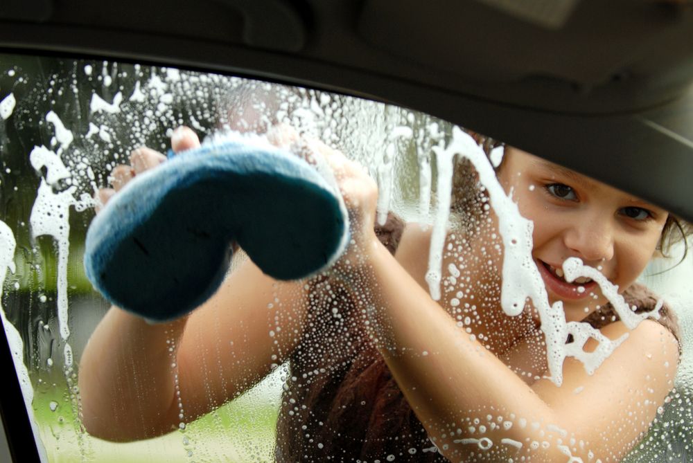 Elementary,Girl,Washing,A,Car,Window,Viewed,From,Inside,The