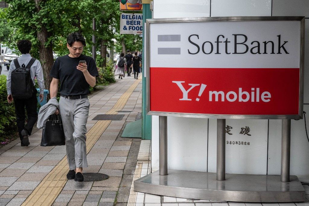Pedestrians walk past a sign for Japanese company SoftBank and Y!Mobile outside a telecommunications shop in Tokyo on May 2, 2024. Japanese investment giant SoftBank Group are expected to announce full year earnings on May 13. (Photo by Yuichi YAMAZAKI / AFP)