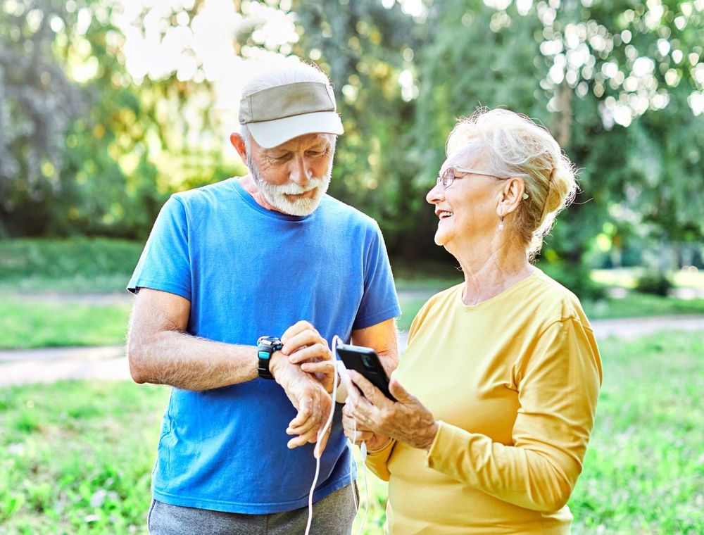 Happy,Active,Senior,Couple,Having,Fun,Using,Smartphone,And,Wearing